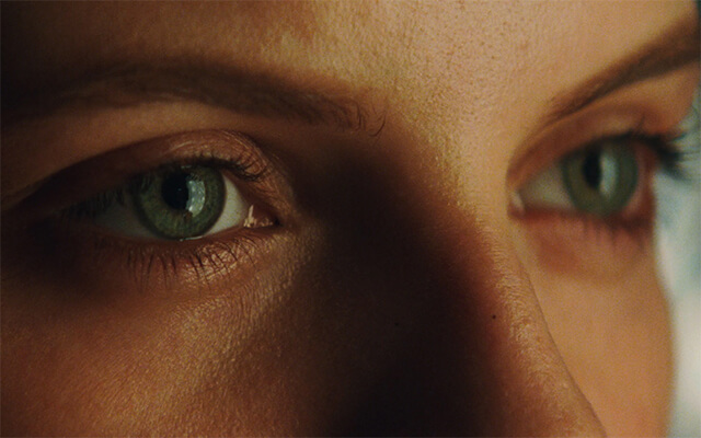 Close detalhado de olhos verdes, sugerindo tensão e foco narrativo em cena cinematográfica.