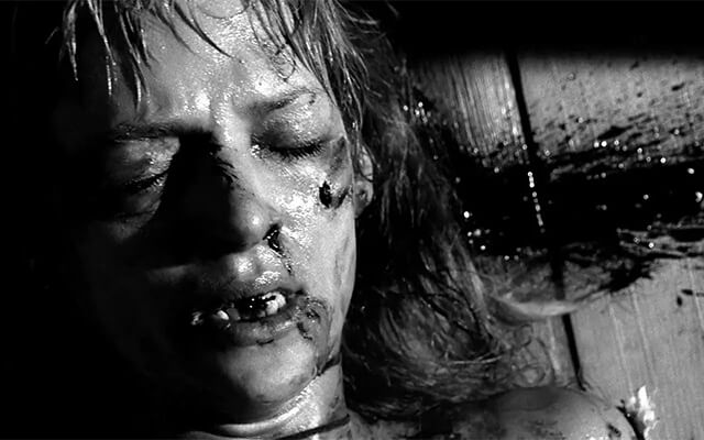A Noiva ensanguentada caída no chão em cena em preto e branco de Kill Bill.